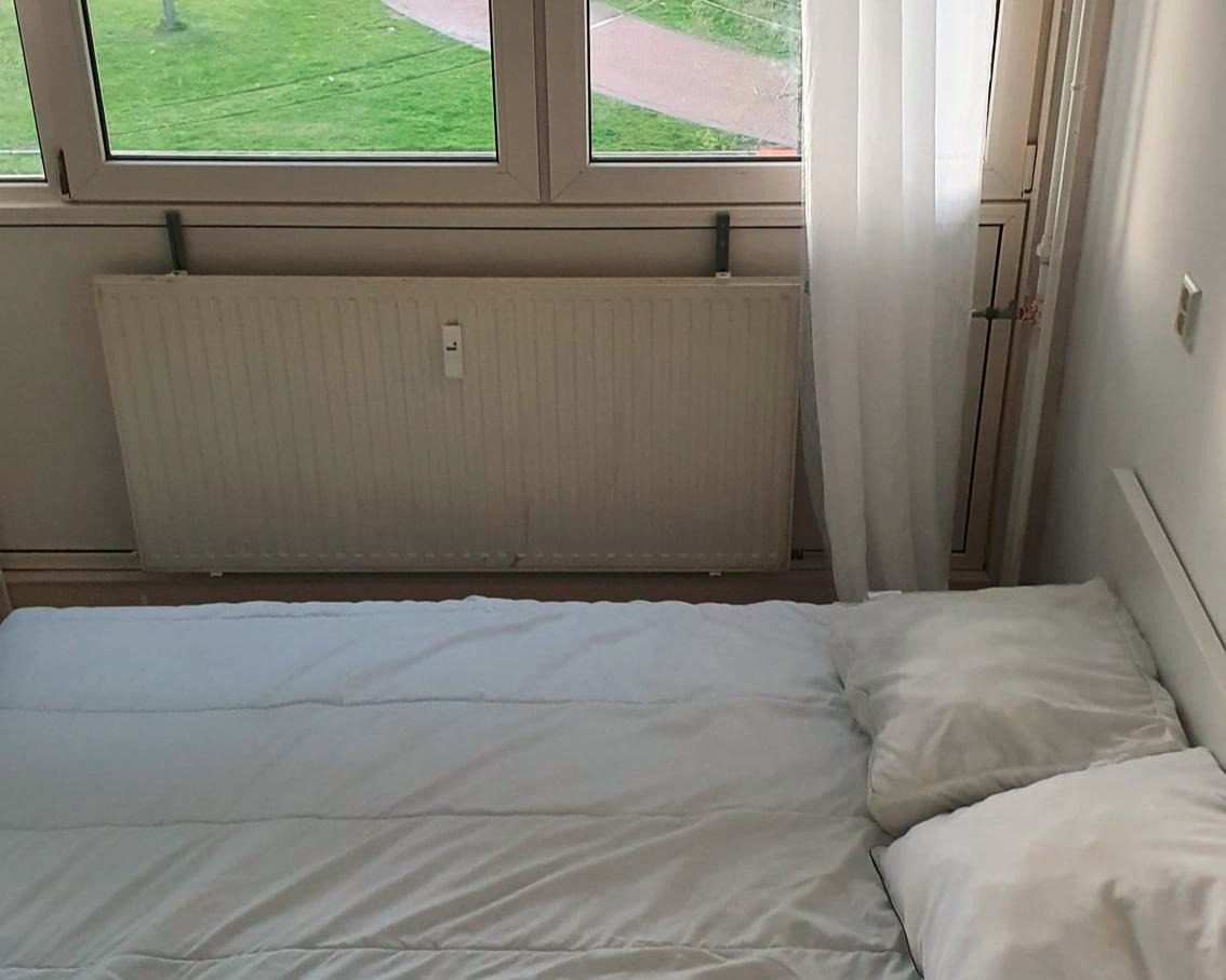 Kamer in ruim met eigen wastafel, koelkas en raam.